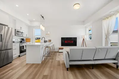 a kitchen and living room with a couch and a table at Aspen - Town House with 2 Bedrooms, Garage Parking, AC & More! in Calgary