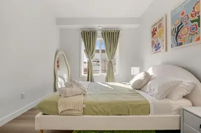 a bedroom with a large bed with a window at Aspen - Town House with 2 Bedrooms, Garage Parking, AC & More! in Calgary