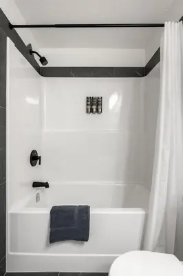 a bathroom with a white tub and a white toilet at Aspen - Town House with 2 Bedrooms, Garage Parking, AC & More! in Calgary