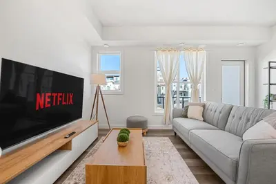 a living room with a couch and a tv at Aspen - Town House with 2 Bedrooms, Garage Parking, AC & More! in Calgary