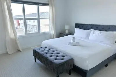 a bedroom with a large bed with a large window at Luxury 3 Bdrm 3 Bath townhome in Chestermere in Chestermere