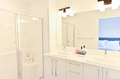 a white bathroom with two sinks and a shower at Luxury 3 Bdrm 3 Bath townhome in Chestermere in Chestermere