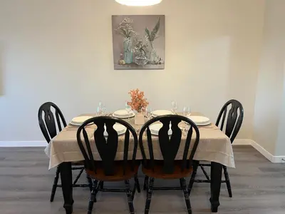 a dining room table with four chairs and a painting at Park View Paradise - Big, Bright, Modern, Fully Stocked in Grande Prairie