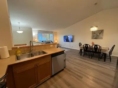 a kitchen with a sink and a dining room at Park View Paradise - Big, Bright, Modern, Fully Stocked in Grande Prairie