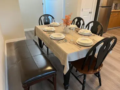 a dining room table with chairs and plates on it at Park View Paradise - Big, Bright, Modern, Fully Stocked in Grande Prairie
