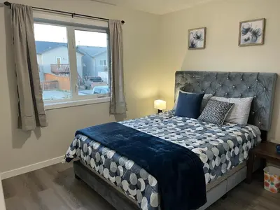 a bedroom with a large bed with a window at Park View Paradise - Big, Bright, Modern, Fully Stocked in Grande Prairie
