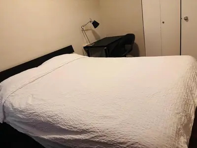 a bedroom with a white bed and a chair at Cozy 2 Bedroom Condo with Parking in Calgary