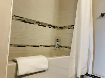 a bath tub with a white shower curtain in a bathroom at Cozy 2 Bedroom Condo with Parking in Calgary