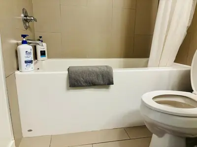 a bathroom with a white toilet and a bath tub at 7th Floor 1 Bedroom Condo with Parking in Calgary