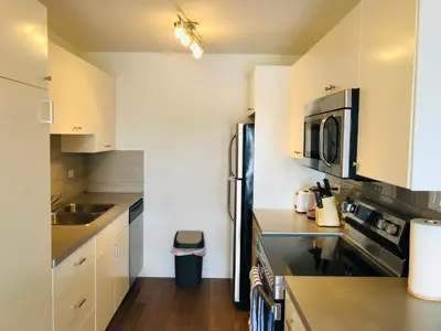 a kitchen with white cabinets and a stainless steel refrigerator at 7th Floor 1 Bedroom Condo with Parking in Calgary