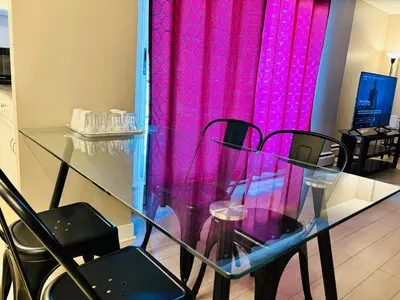 a glass table with black chairs and a pink curtain at 6th Floor 2 Bedroom Condo with Parking in Calgary
