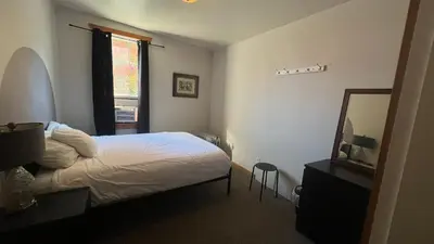 a bedroom with a bed and a mirror and a window at Mountain Shadow Hostel in Rossland