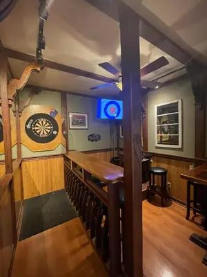 a bar with a wooden table and a dartboard on the wall at Mountain Shadow Hostel in Rossland