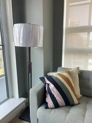 a lamp sitting next to a couch with a pillow at Brand new Stylists Richmond central 2B2BR in Richmond