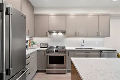 a kitchen with stainless steel appliances and white cabinets at The Beach House at Saratoga Modern Beach Oasis in Oyster Bay