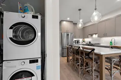 a kitchen with a washing machine and a dining room at The Beach House at Saratoga Modern Beach Oasis in Oyster Bay