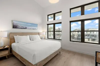 a white bedroom with a bed and windows at The Beach House at Saratoga Modern Beach Oasis in Oyster Bay