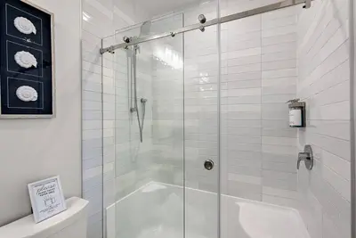 a bathroom with a glass shower with a toilet at The Beach House at Saratoga Modern Beach Oasis in Oyster Bay