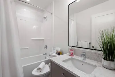 a bathroom with a sink and a toilet and a mirror at The Beach House at Saratoga Modern Beach Oasis in Oyster Bay