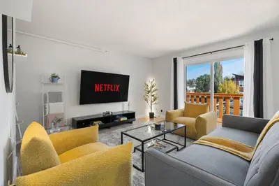 a living room with yellow chairs and a tv at Spacious 4-Bedroom Retreat Near Bow River with Foosball, Dart Board, Movie Room in Calgary