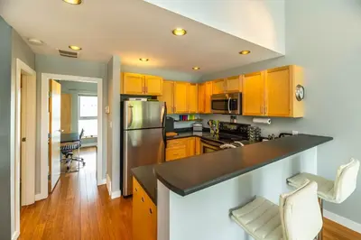 a kitchen with wooden cabinets and a stainless steel refrigerator at NN - The Kit 4 - Downtown 1-Bed 1-Bath in Whitehorse