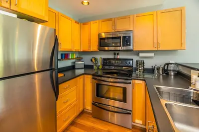 a kitchen with wooden cabinets and stainless steel appliances at NN - The Kit 4 - Downtown 1-Bed 1-Bath in Whitehorse