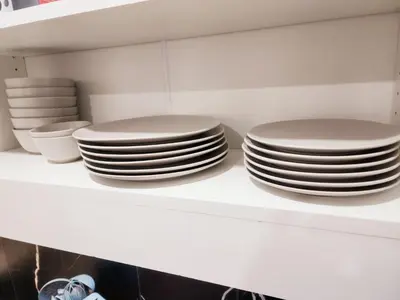 a stack of plates on a shelf in a kitchen at Charming & Compact Retreat in St. Albert
