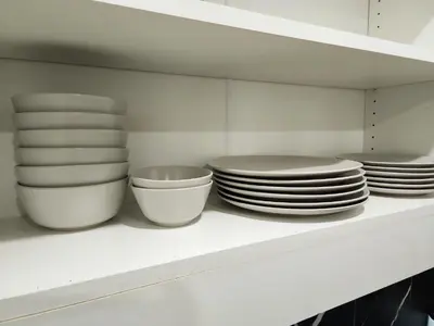 a white shelf with plates and bowls on it at Charming & Compact Retreat in St. Albert