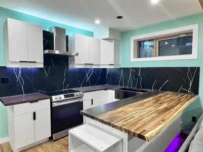 a kitchen with white cabinets and a wooden counter top at Charming & Compact Retreat in St. Albert
