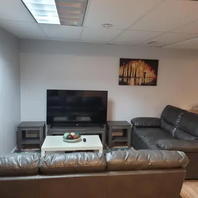 a living room with a leather couch and a flat screen tv at Fabulous Room in Edmonton