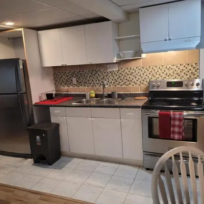 a kitchen with white cabinets and a sink and a refrigerator at Fabulous Room in Edmonton