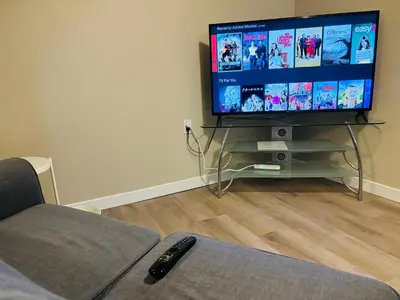 a living room with a flat screen tv and a couch at Walkout Basement Suite with Free Street Parking in Calgary