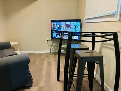 a room with a table and two stools and a television at Walkout Basement Suite with Free Street Parking in Calgary