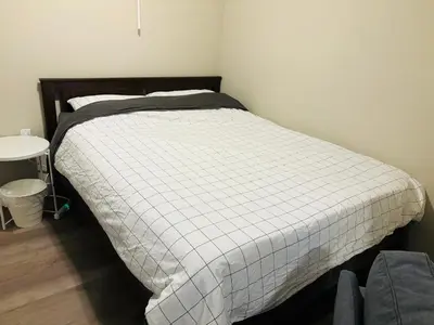 a bedroom with a bed with a white blanket at Walkout Basement Suite with Free Street Parking in Calgary