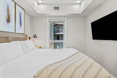 a white bedroom with a bed and a flat screen tv at Pool and hot tub Stunning 2Bd haven in the Rockies in Dead Man's Flats