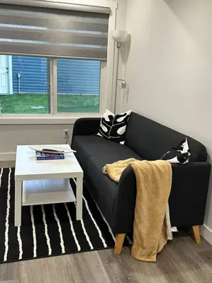 a living room with a black couch and a table at The Urban Nest in Calgary