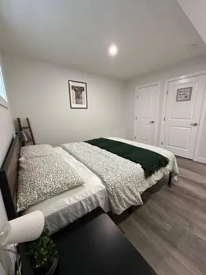 a bedroom with a bed with a green blanket on it at The Urban Nest in Calgary