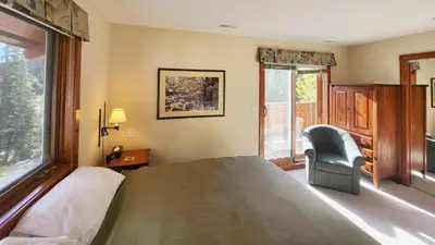 a bedroom with a bed and a chair and a window at Timberline Village #46 home in Sun Peaks