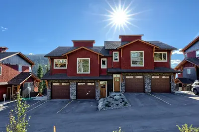 a red house with two garage doors in a parking lot at Powder Heights #15 home in Sun Peaks