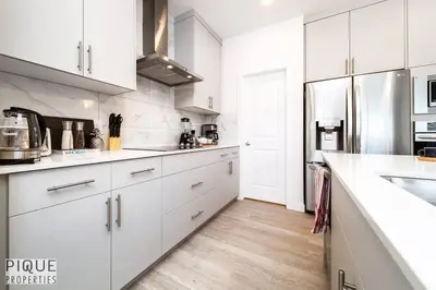 a white kitchen with white cabinets and a sink at Modern Executive Home-Sleeps12-KingBeds-FullHouse in Edmonton