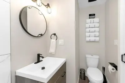 a white bathroom with a sink and a mirror at BunkBedDreams,10 Beds,Near Rogers place and Nait in Edmonton