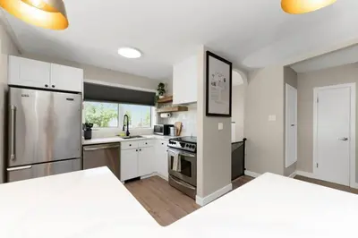 a kitchen with white cabinets and a stainless steel refrigerator at BunkBedDreams,10 Beds,Near Rogers place and Nait in Edmonton