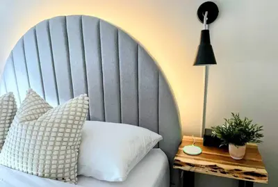 a bed with a large headboard and a table with a lamp at BunkBedDreams,10 Beds,Near Rogers place and Nait in Edmonton