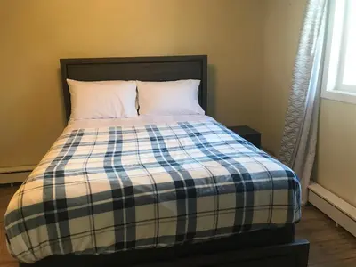 a bed with a blue and white plaid blanket at Northern Rainbow Upper Level Suite in House in Yellowknife
