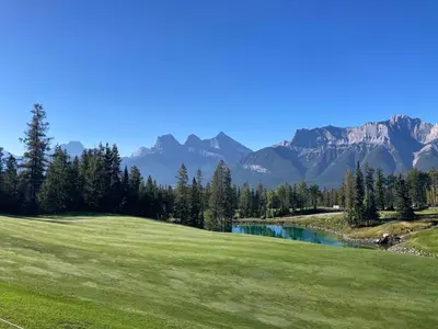 a golf course with mountains in the background at Premium King suite with views and pool in Canmore