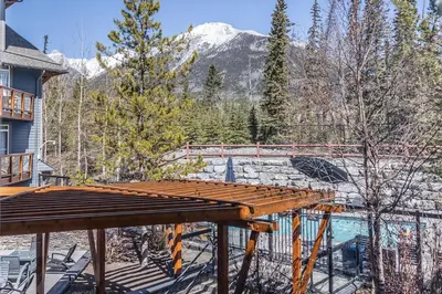 a deck with a pool and mountains in the background at Premium King suite with views and pool in Canmore
