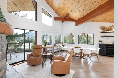 a dining room with a table and chairs and windows at White Gold Chalet - Spacious Family-Friendly Chalet, Hot Tub, Mountain Views, Log Fireplace in Whistler