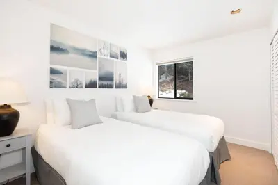 two beds in a bedroom with white walls at White Gold Chalet - Spacious Family-Friendly Chalet, Hot Tub, Mountain Views, Log Fireplace in Whistler