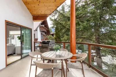 a patio with a table and chairs on a balcony at White Gold Chalet - Spacious Family-Friendly Chalet, Hot Tub, Mountain Views, Log Fireplace in Whistler