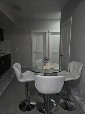 a dining room with a glass table and white chairs at Wola's Place in Calgary